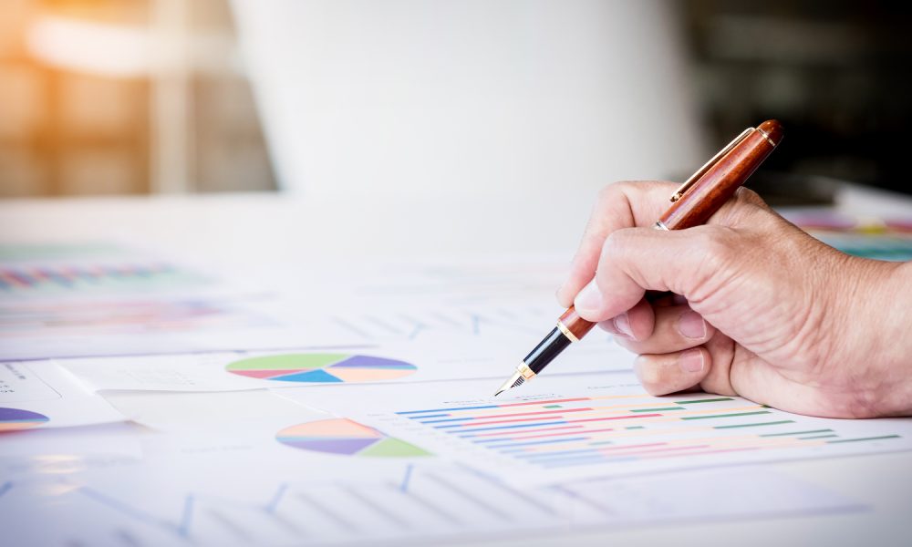 Working process startup. Businessman working at the wood table with new finance project. Modern notebook on table. Pen holding hand